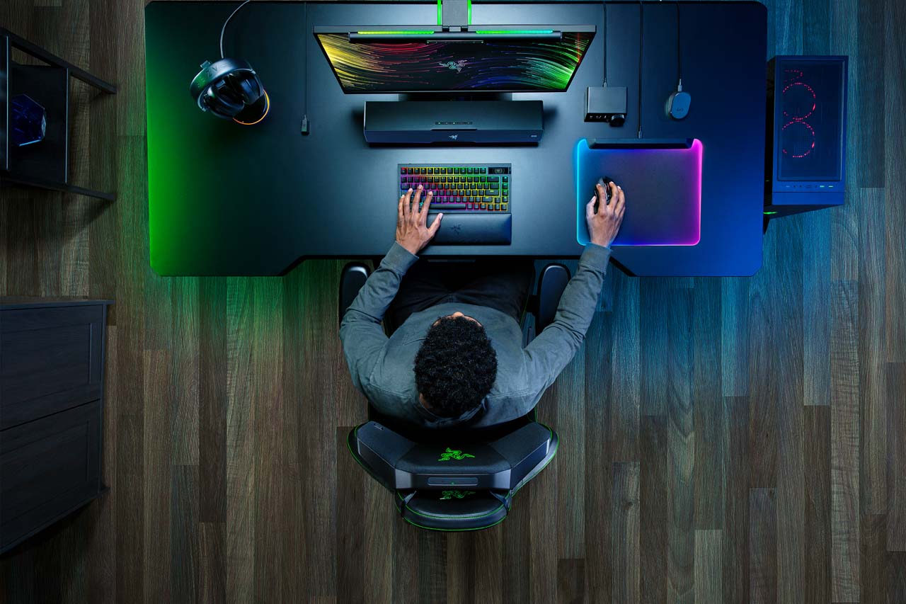 Installation gaming avec coussin audio Razer Clio intégré à une chaise, éclairage RGB et setup Razer complet