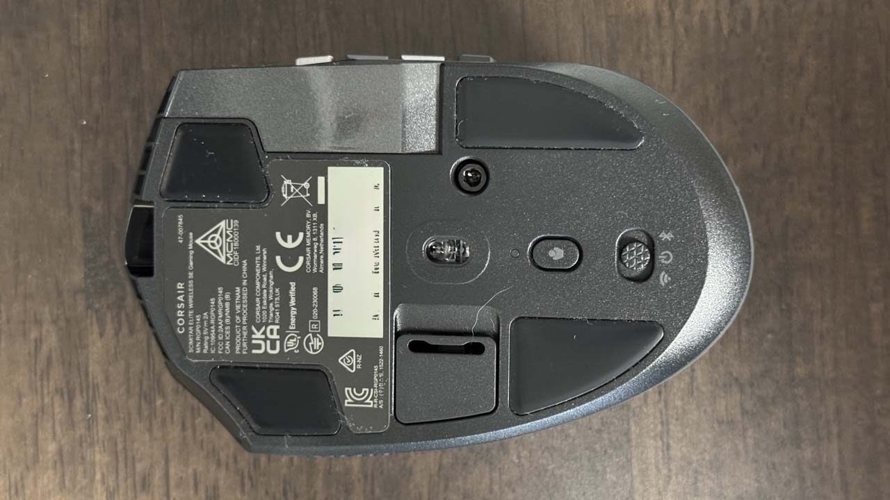 Vue du dessous de la Corsair Scimitar Elite Wireless SE montrant les patins et interrupteurs
