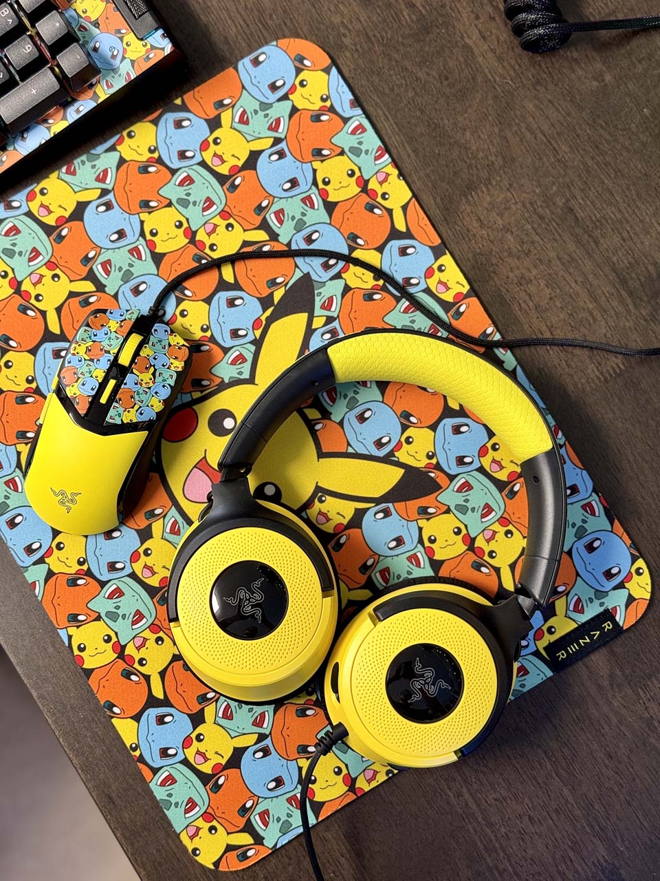 Casque Kraken V4X, souris Cobra et tapis Gigantus V2 Pokémon posés sur un bureau, avec motifs de Pikachu, Salamèche, Bulbizarre et Carapuce
